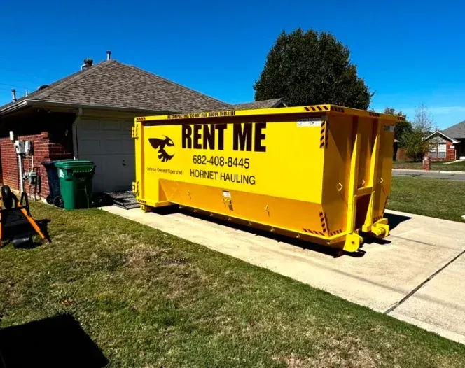 A yellow dumpster is parked in front of a house.