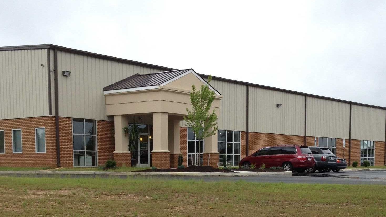 A red van is parked in front of a large building