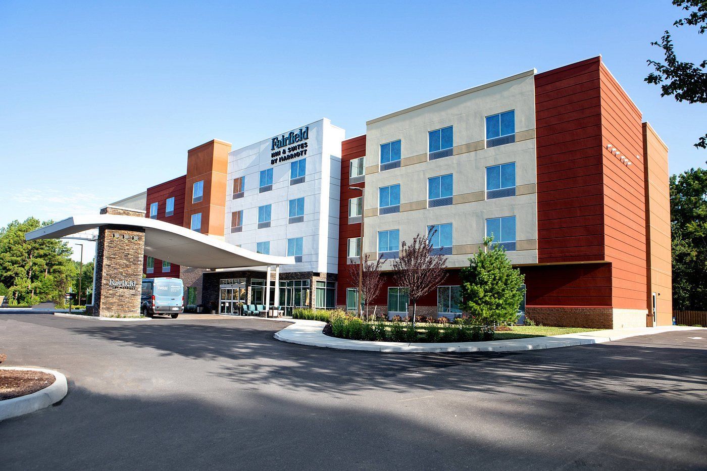 A large hotel with a lot of windows is surrounded by trees.