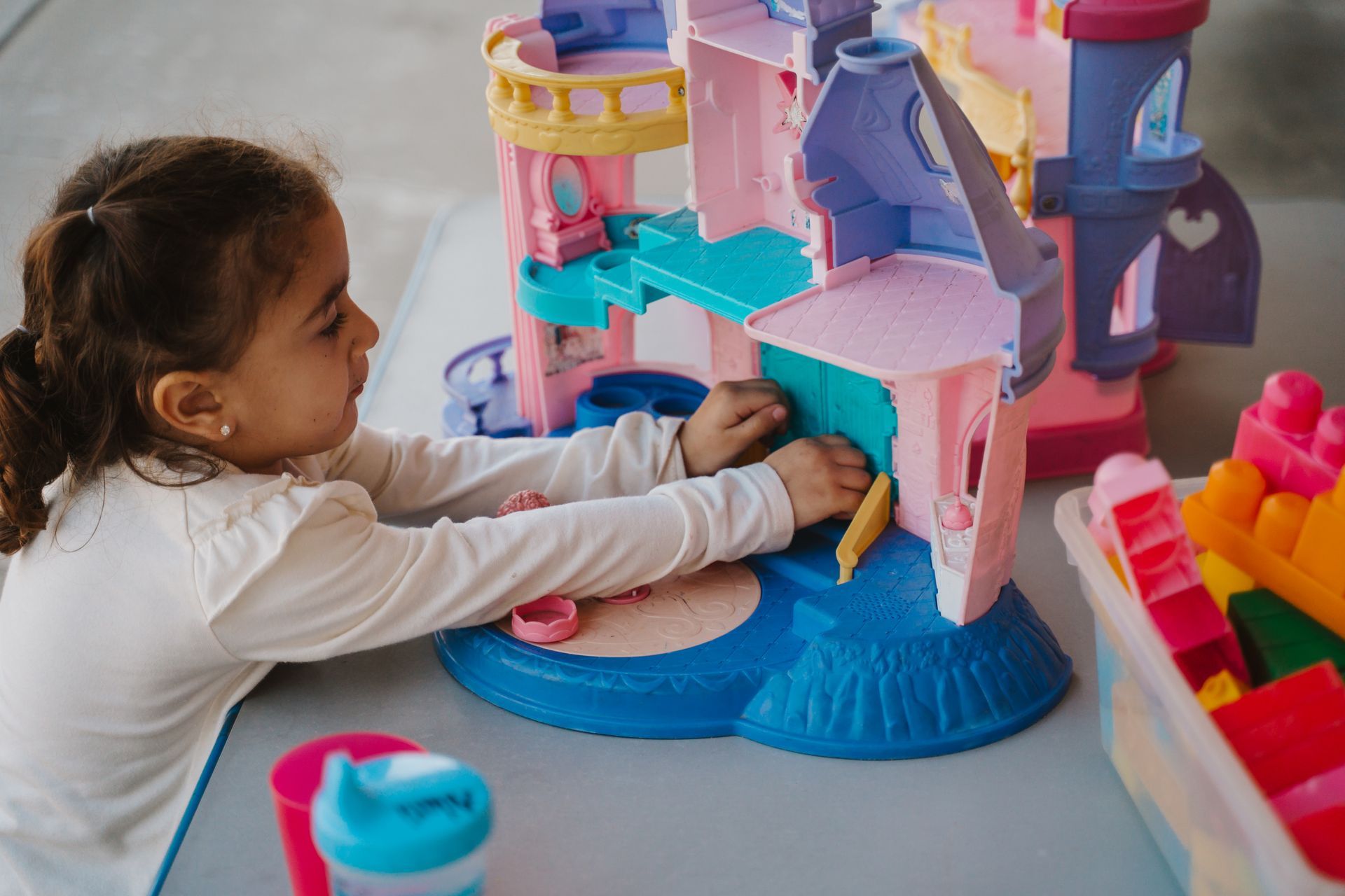 A little girl is playing with a pink doll house