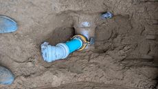 A man is working on a pipe in the dirt.