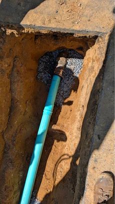Two pipes are being installed in a trench in the dirt.