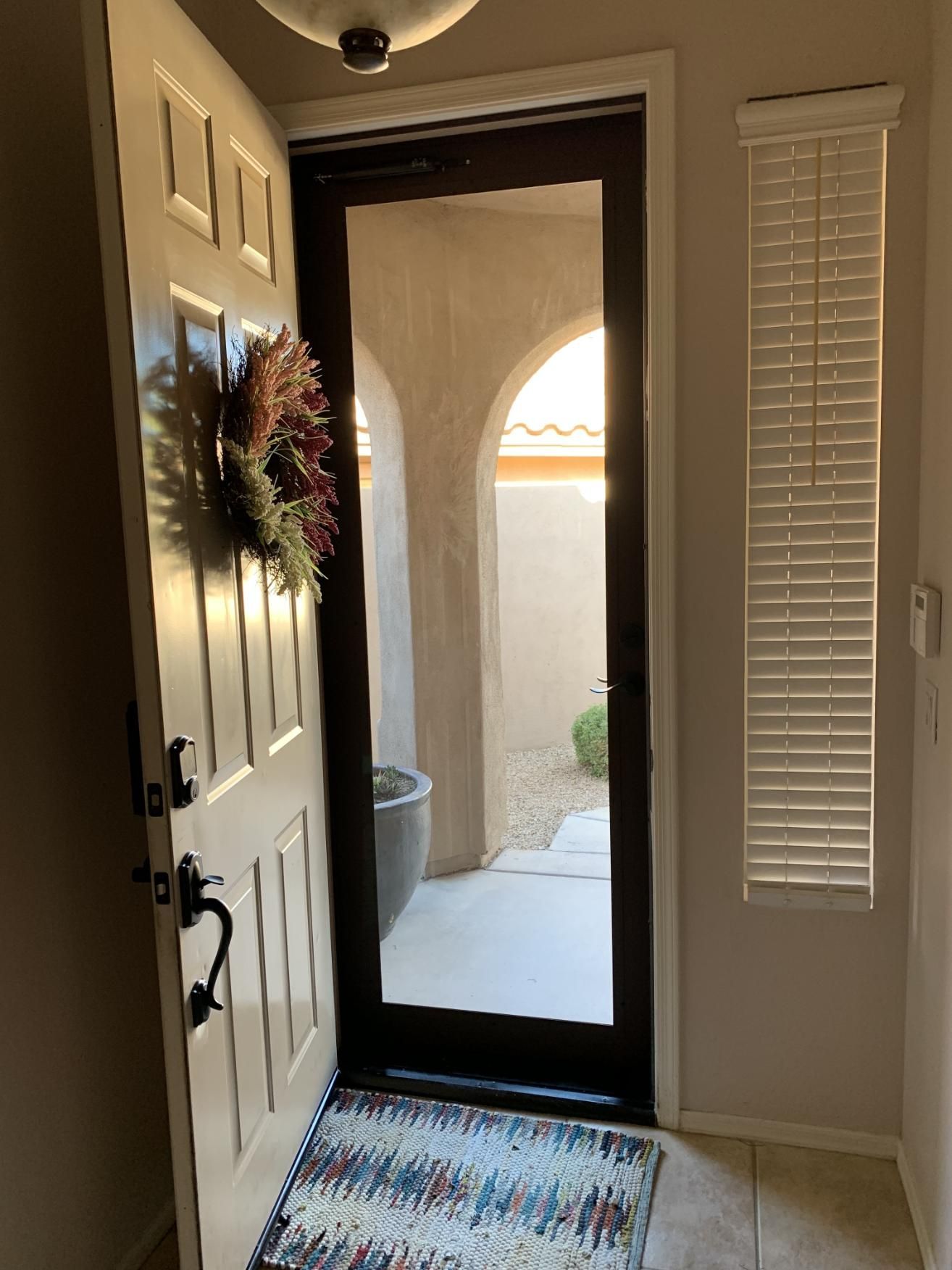A door with a wreath on it and a rug in front of it.