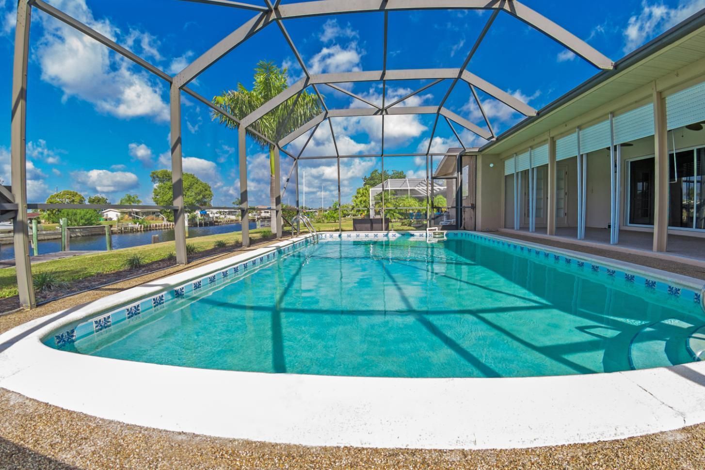 There is a large swimming pool in the backyard of a house.