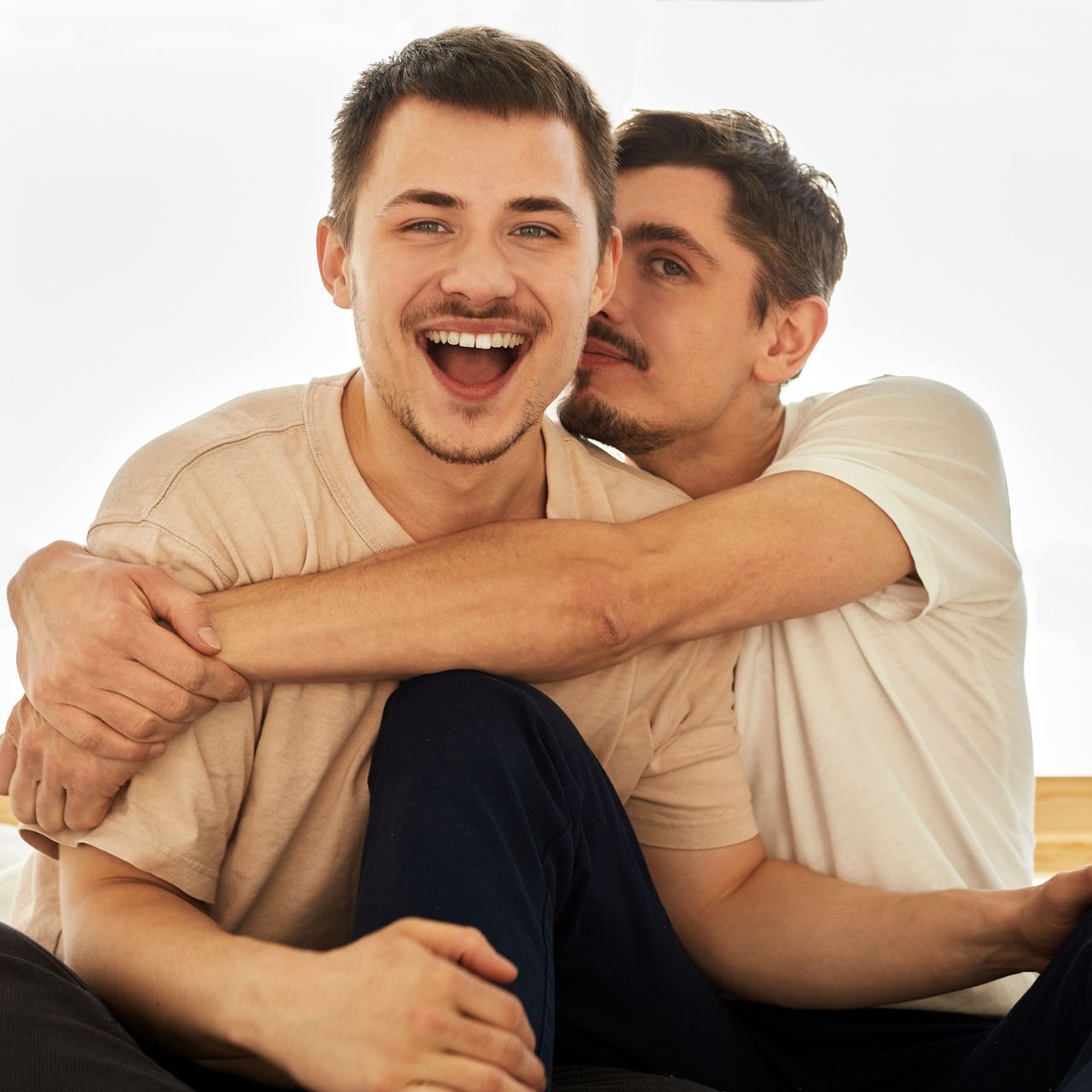 A man is kissing another man on the cheek.