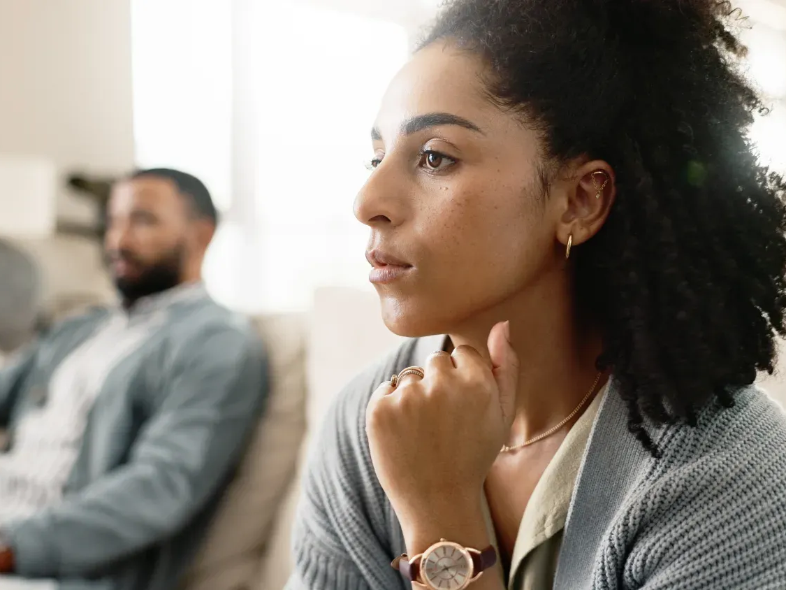 A man and a woman are sitting at a table with papers and wedding rings on it.