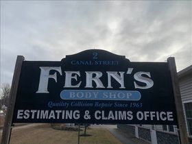 Sign for Fern's Body Shop: black with white text, address, and blue "Body Shop" banner.