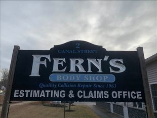 Sign for Fern's Body Shop: black with white text, address, and blue "Body Shop" banner.