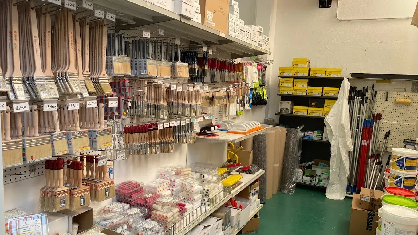 Il corridoio di un negozio al dettaglio con file di pennelli appesi a ganci e vari articoli per la pittura sugli scaffali.