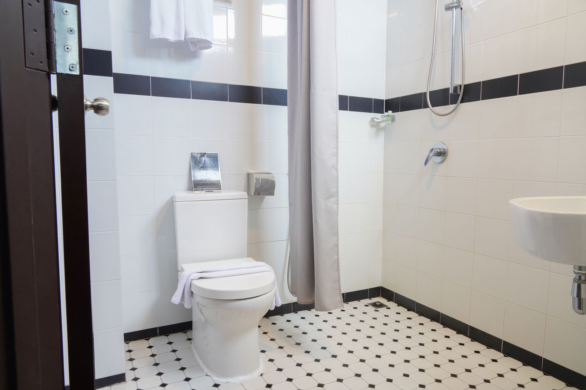 A bathroom with a toilet , sink and shower.