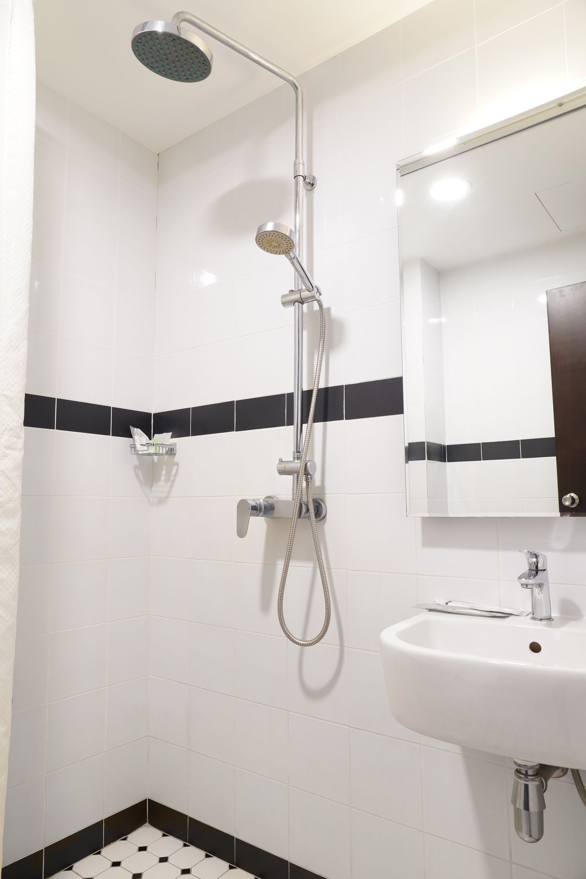 A bathroom with a sink , shower and mirror.
