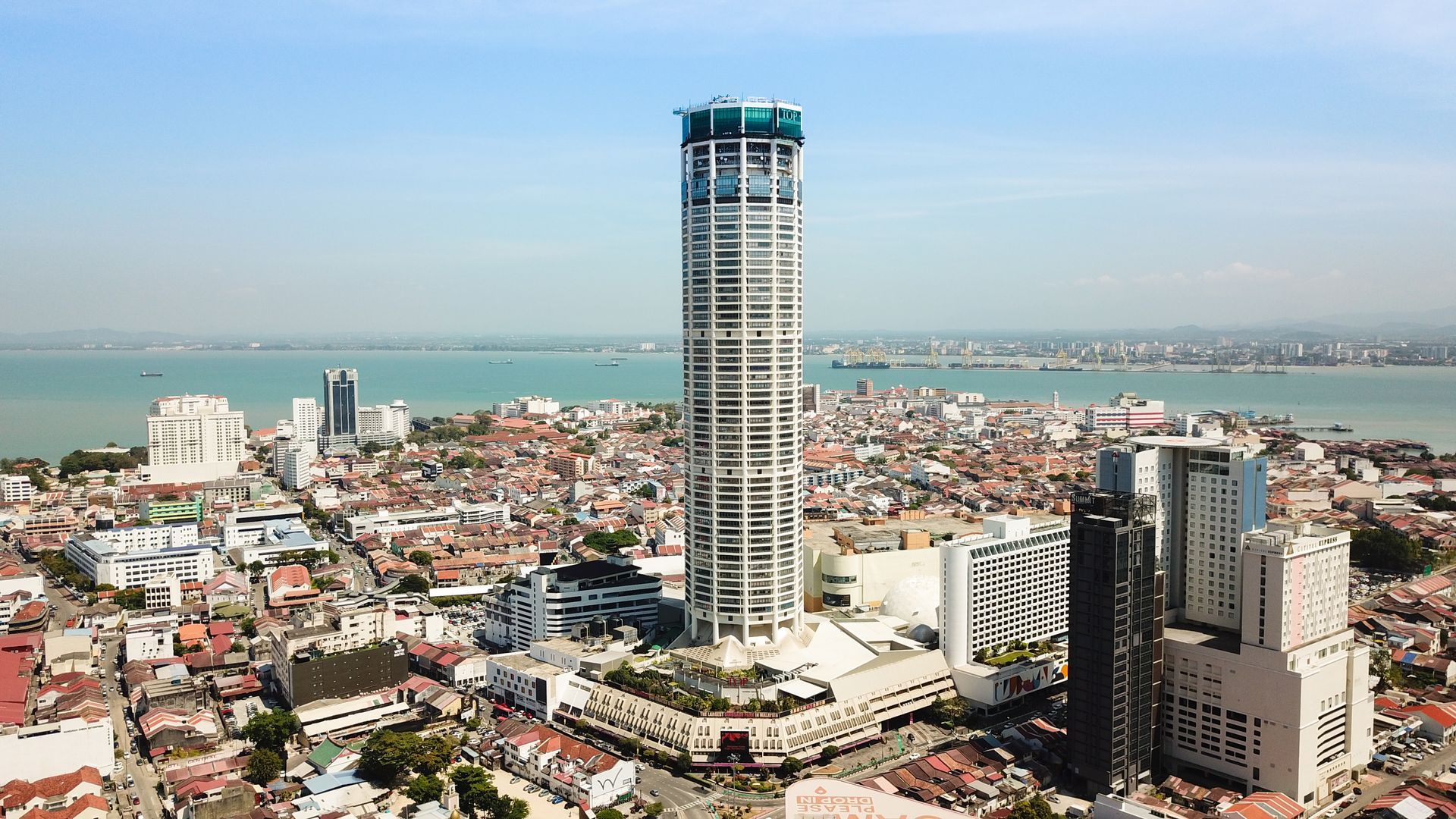An aerial view of a city with a tall building in the middle.