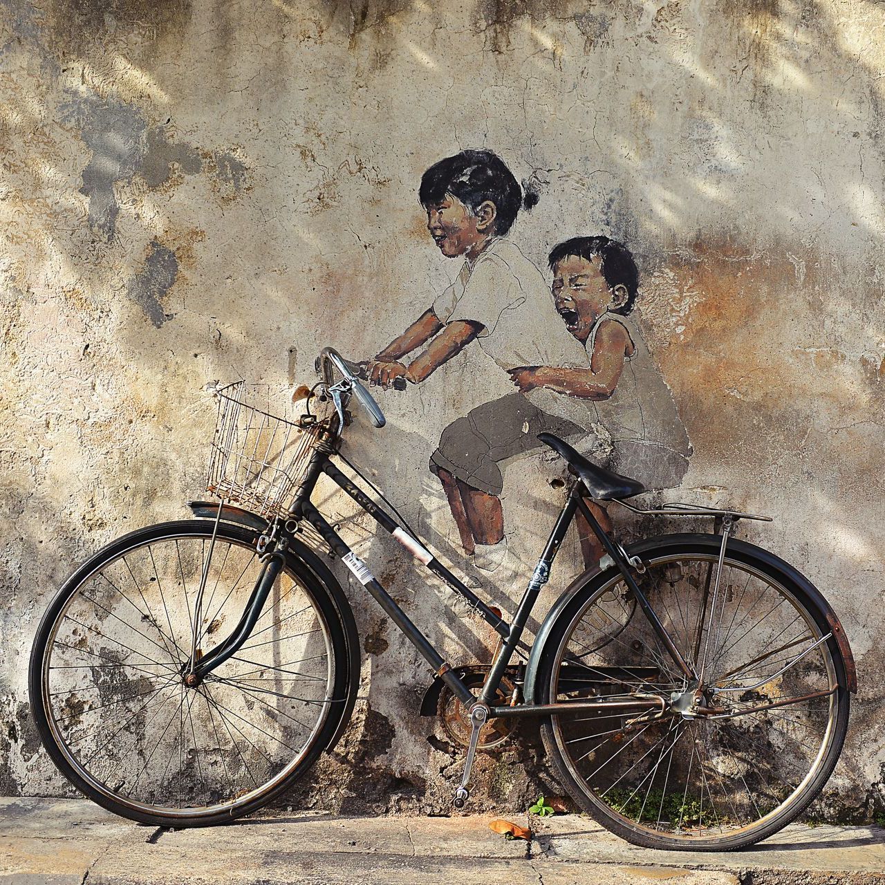A painting of two children riding a bike on a wall