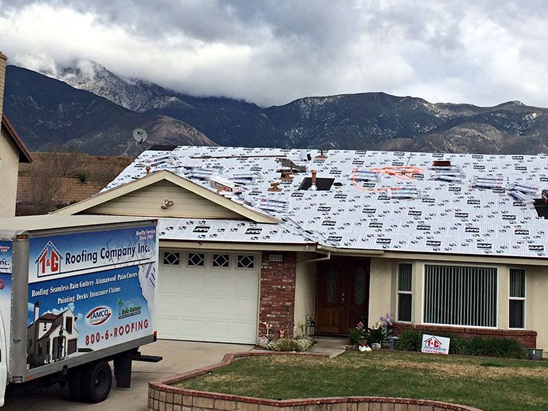 Snow-dusted suburban house with mountains in the background and a moving truck parked in front.