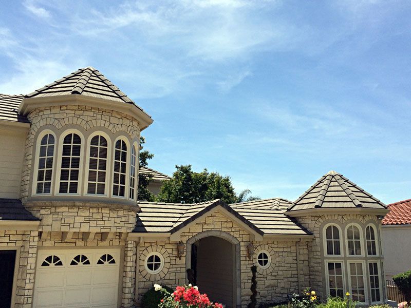 Stone house with turret, arched windows, and a tiled roof under a clear blue sky