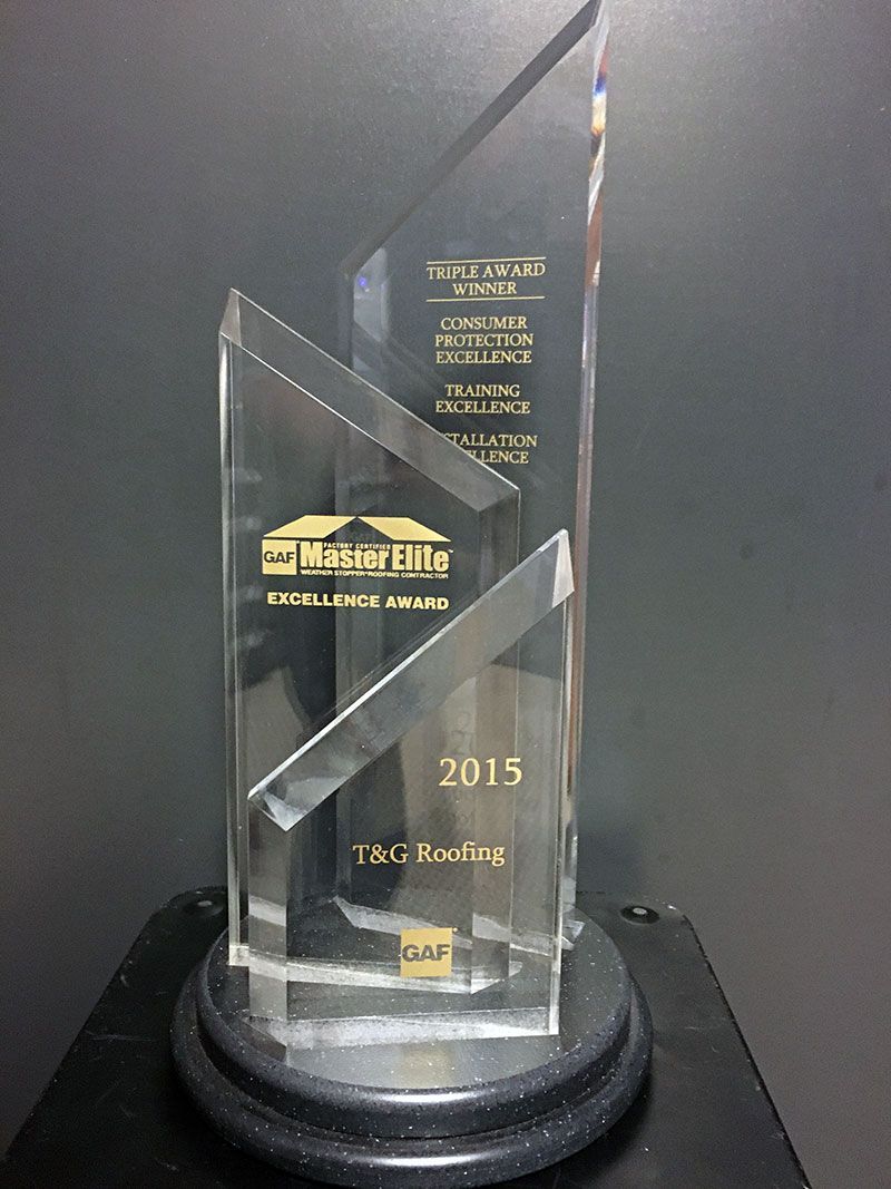 Clear glass award trophy with gold text on a black base against a dark background
