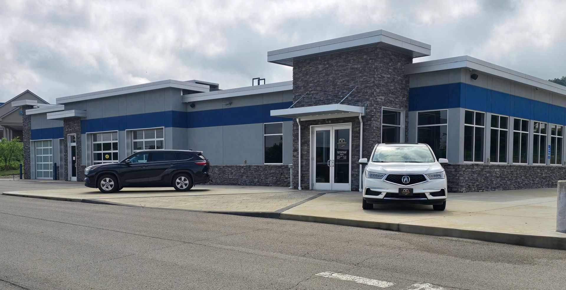 Modern commercial building with blue accents and two parked cars in front | Strother Brothers Auto Care