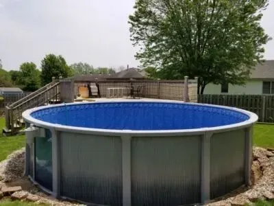 A large swimming pool is sitting on top of a lush green lawn in a backyard.