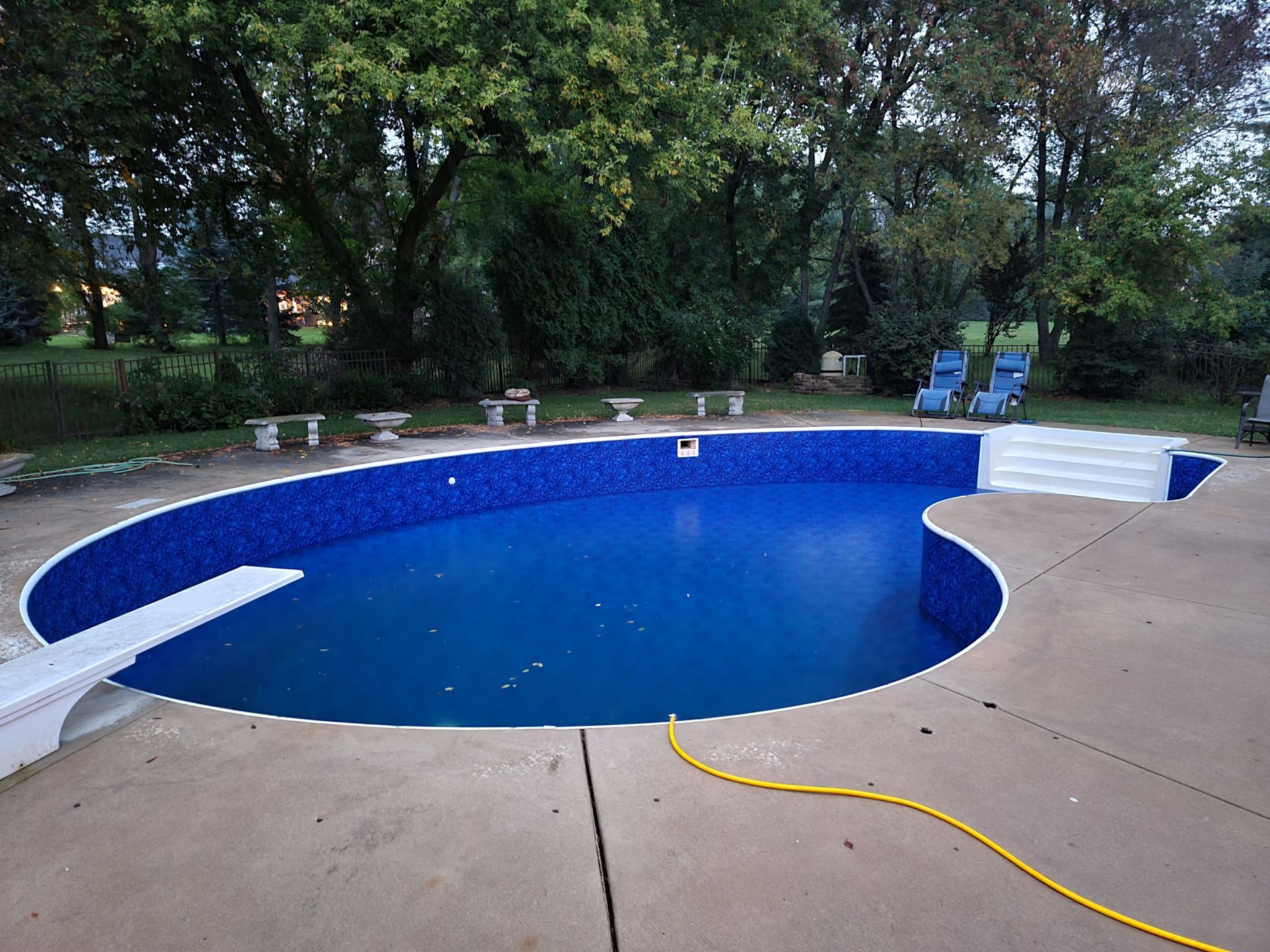 a bean shaped in ground pool with a diving board