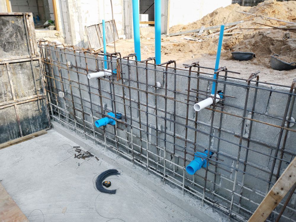 A concrete wall with pipes attached to it is being built.