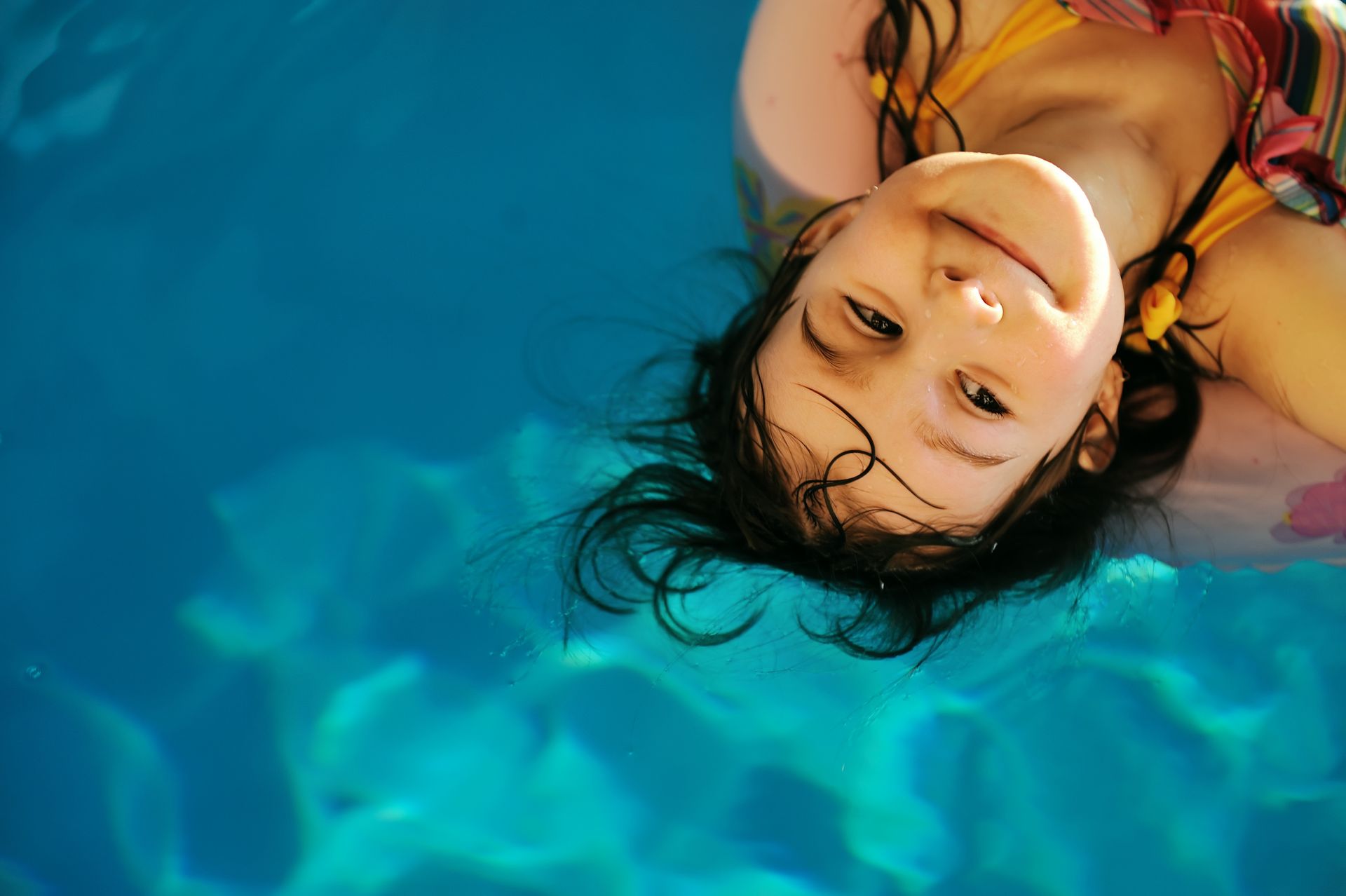 a little girl in a backyard swimming pool -- inground swimming pool