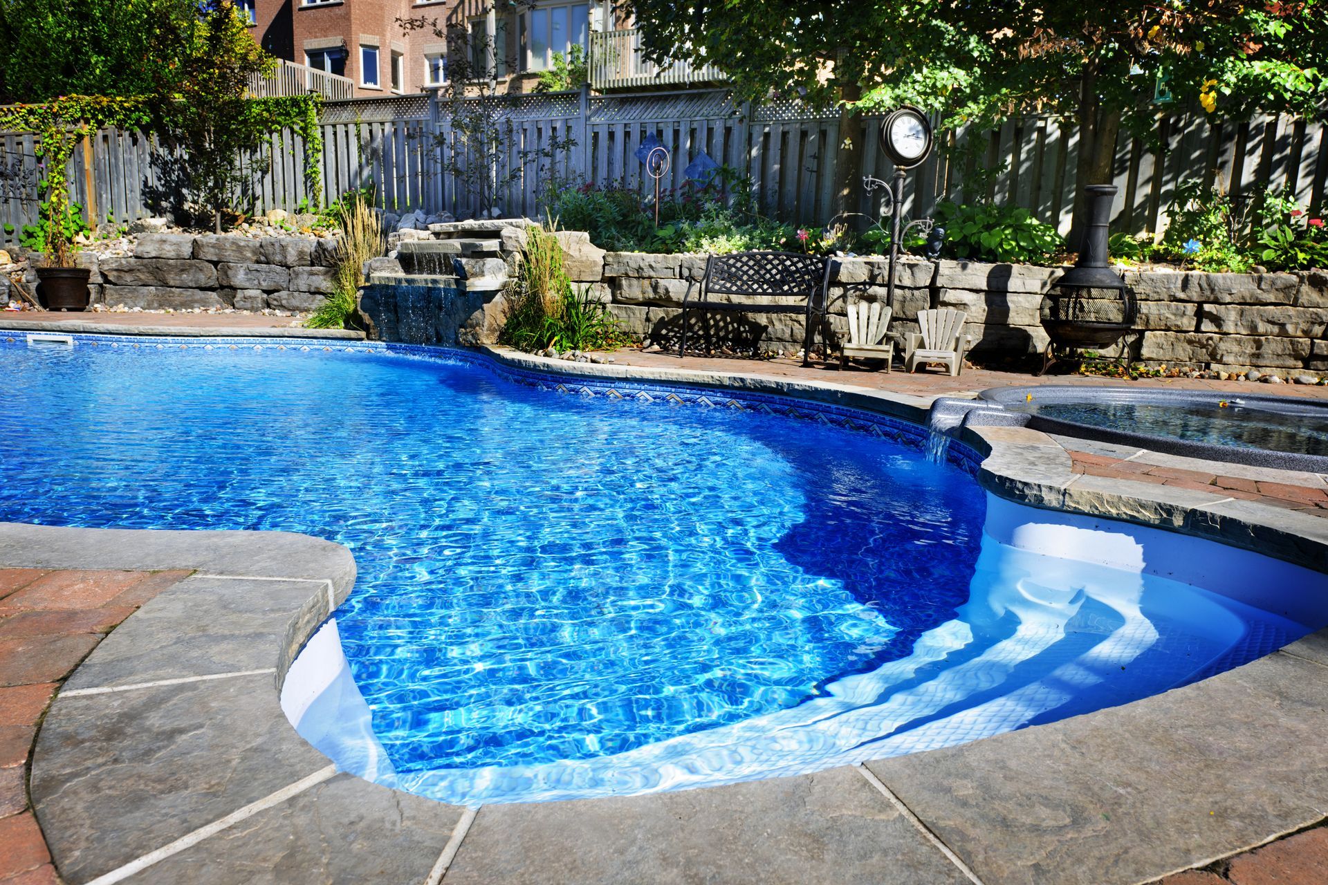 a large concrete swimming pool with a waterfall in the backyard