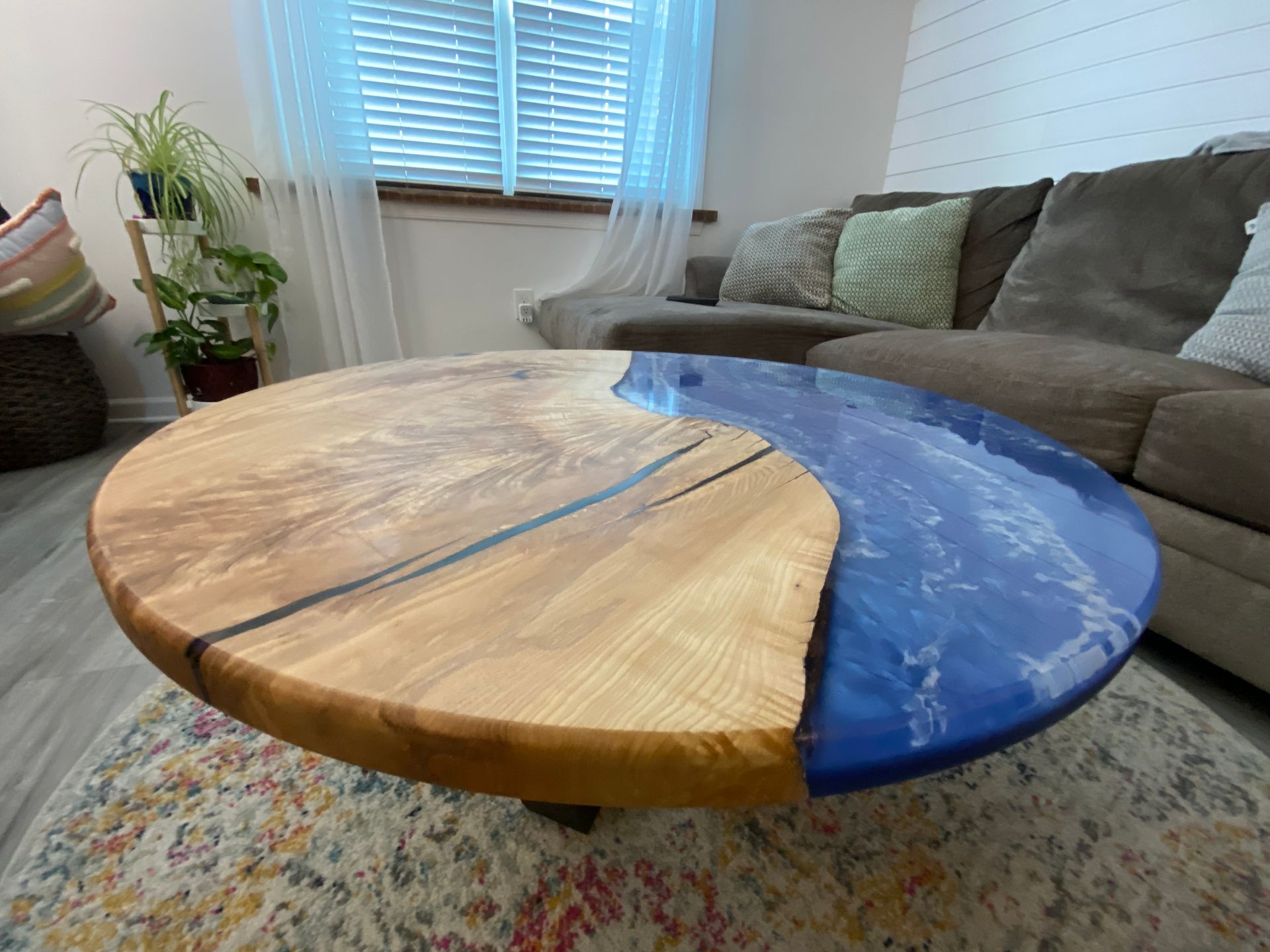 A wooden coffee table with a blue top is sitting in a living room next to a couch.