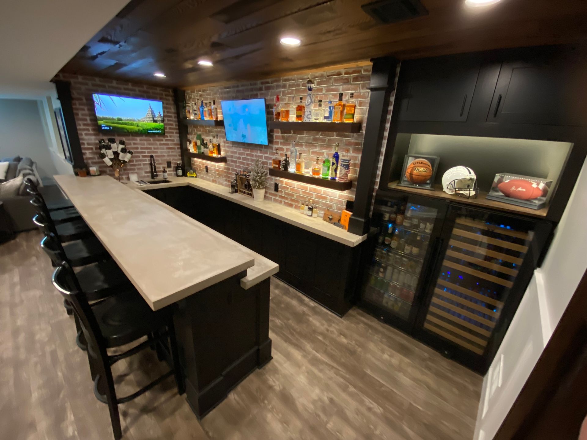 A bar in a basement with a brick wall and a refrigerator.