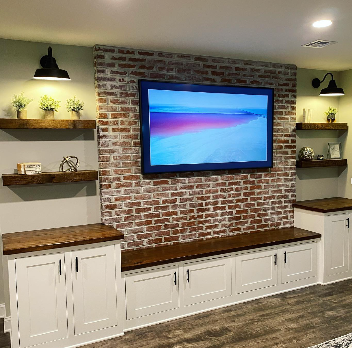 A large flat screen tv is mounted on a brick wall in a living room.