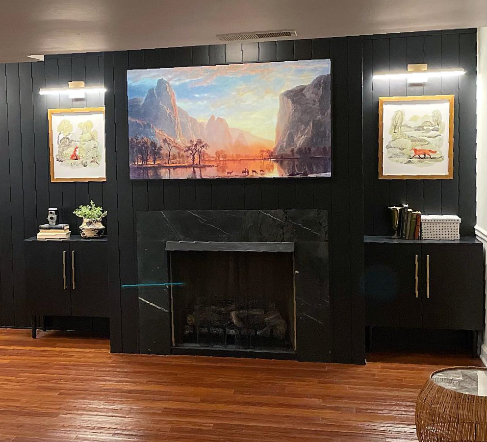 A living room with a fireplace and a painting on the wall.