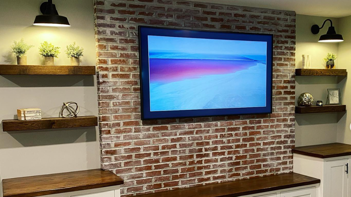 a flat screen tv is mounted on a brick wall . a flat screen tv is mounted on a brick wall .