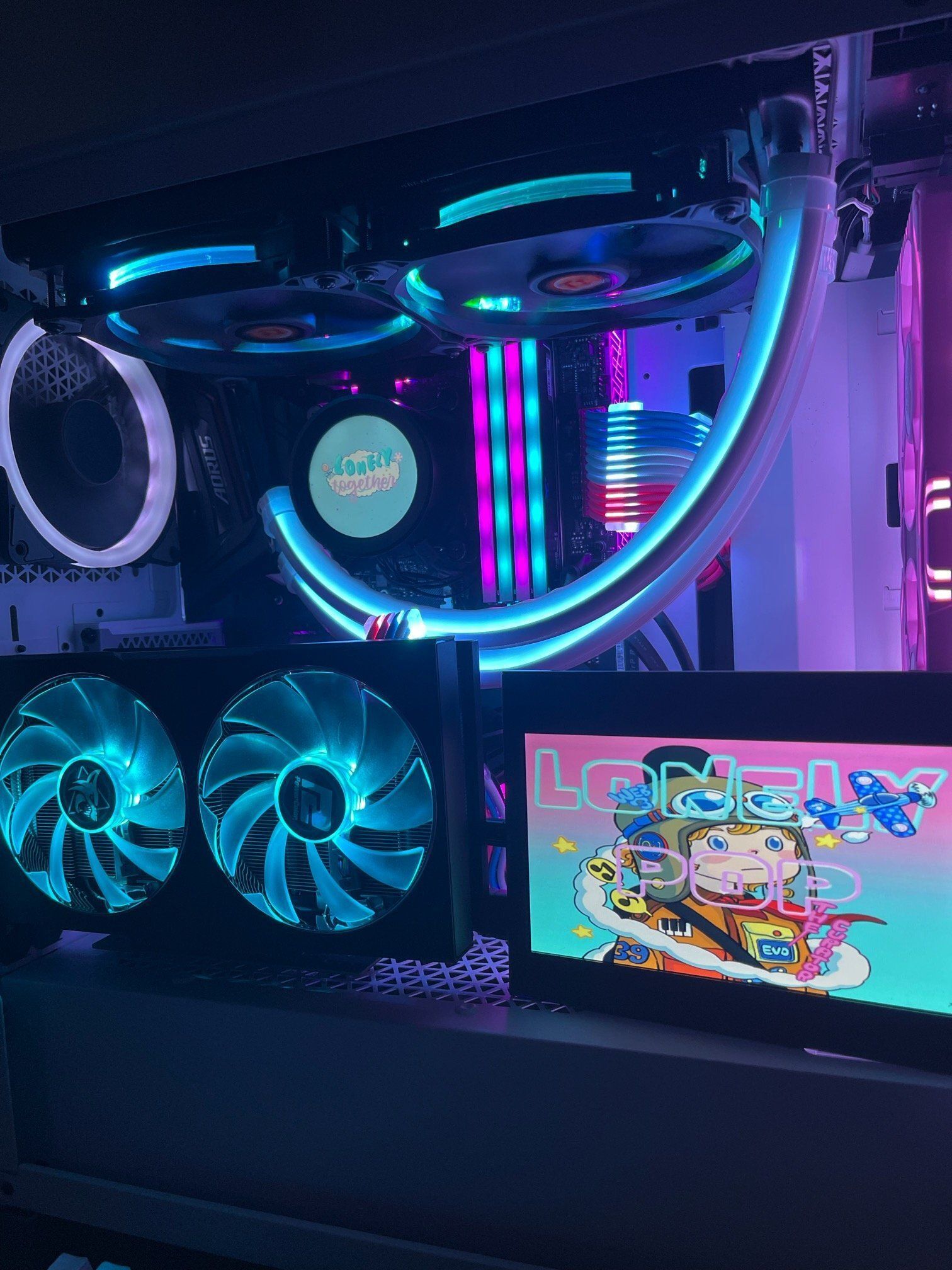 A custom PC rig with bright blue and pink lighting, a small display showing colorful art, and a keyboard.