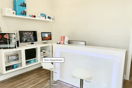 Tech department counter with a computer, shelves, and a white modern design.