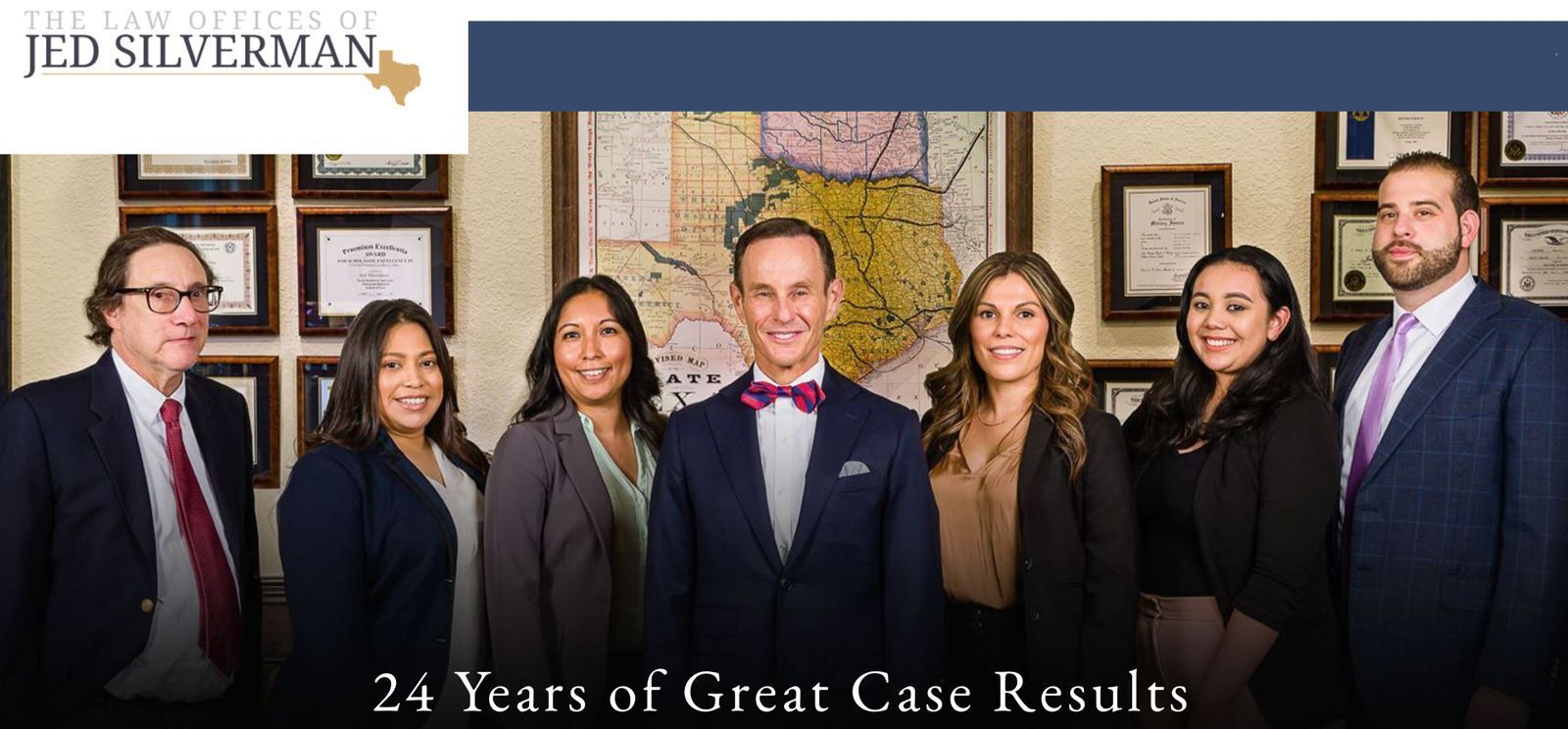 Law office team standing together, smiling. Includes Jed Silverman, and women and men in suits, in front of a map.