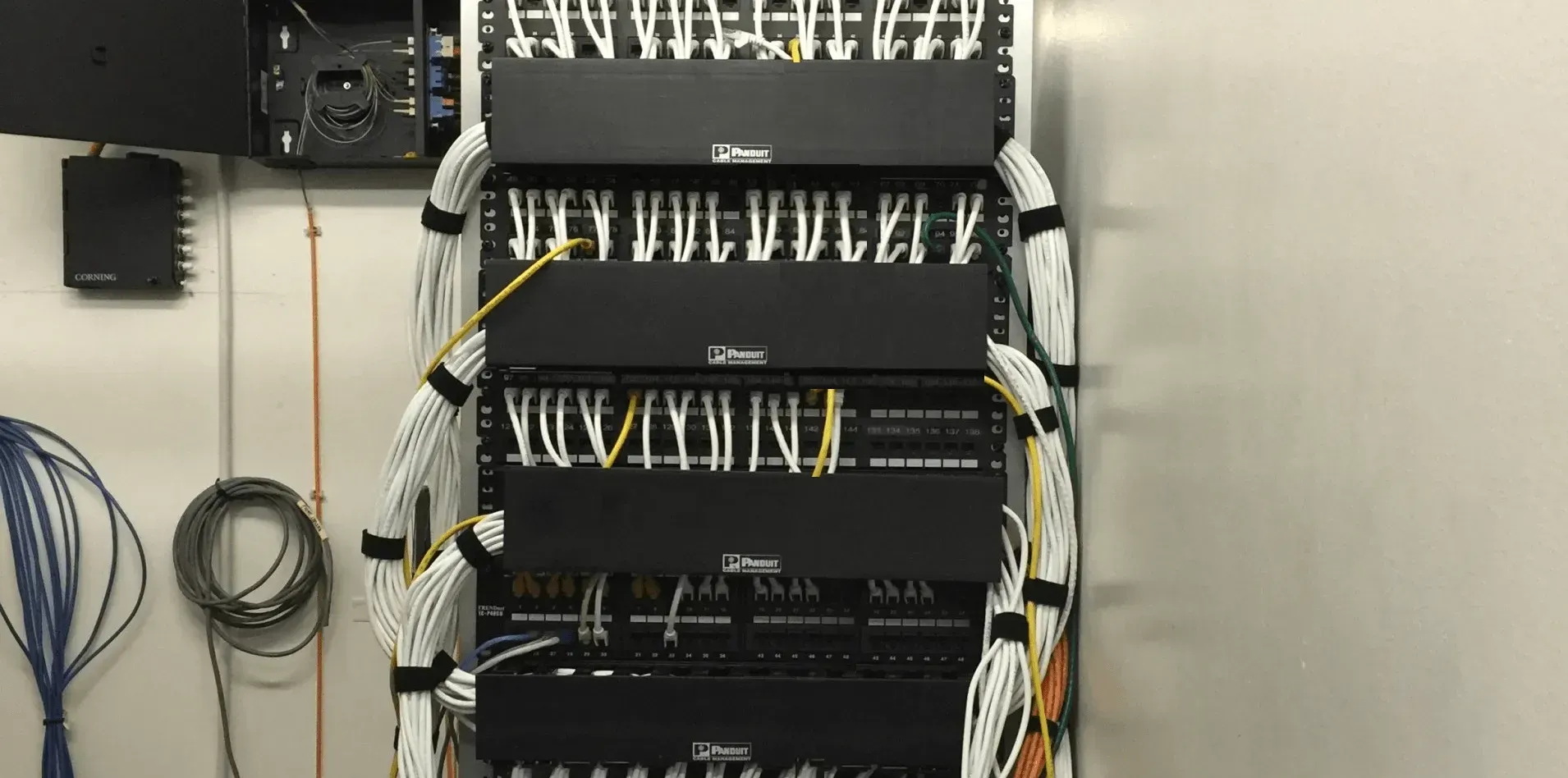 Network server rack with multiple black components and a mass of white and yellow cables.