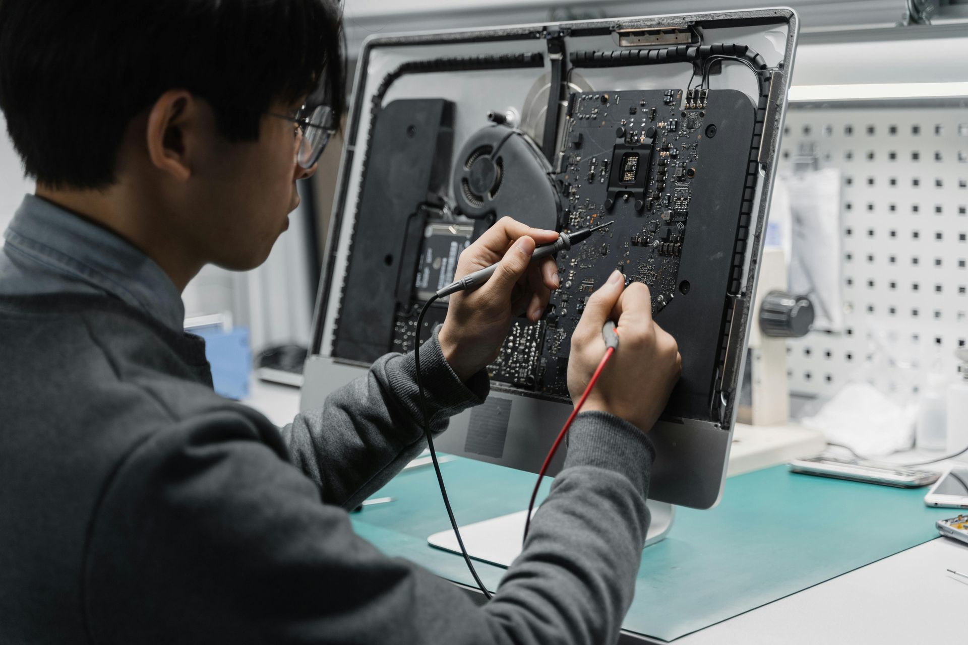 A person repairs a computer's motherboard with probes. 