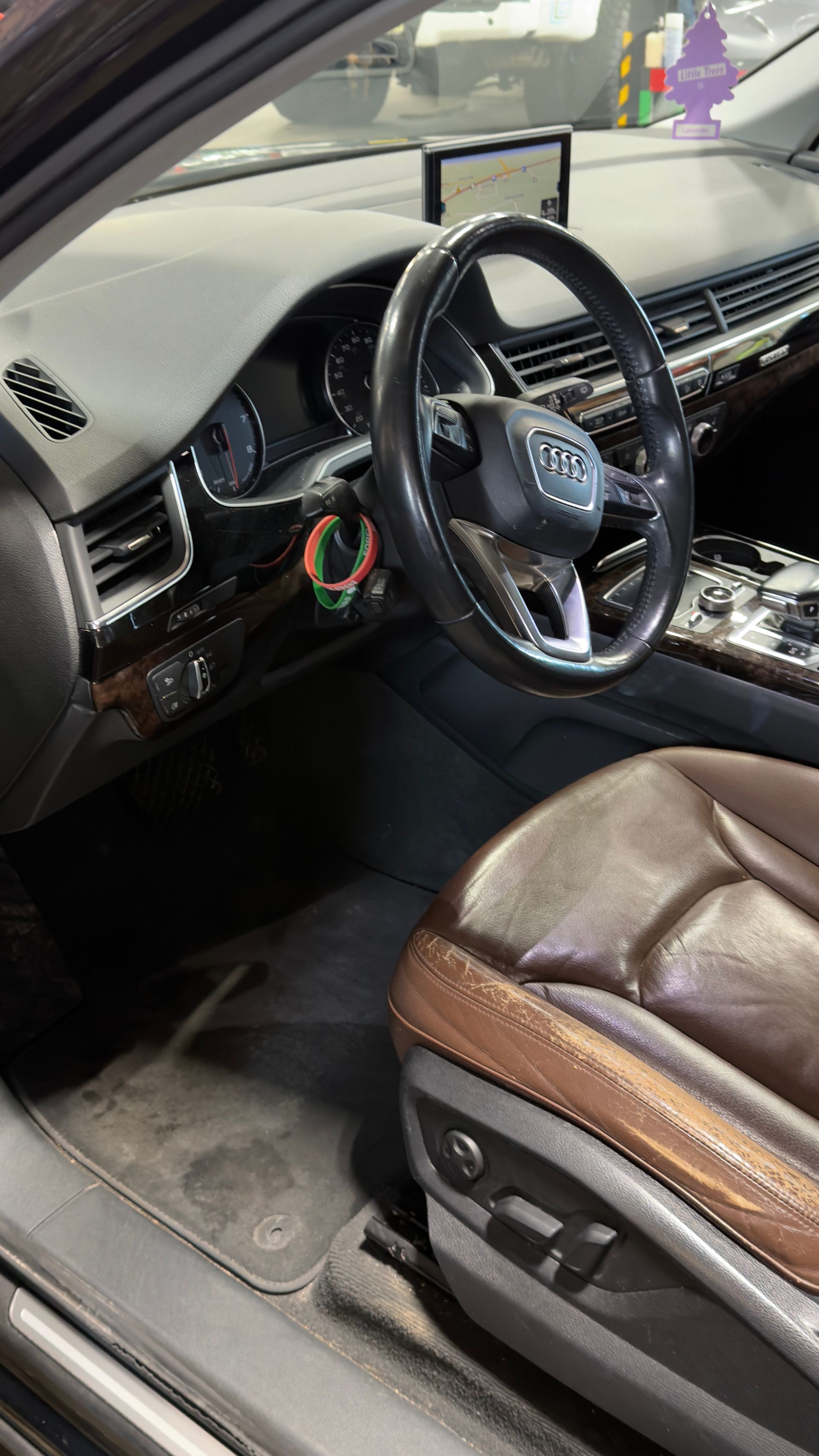 Car interior with brown leather seat, steering wheel, dashboard, and center console.