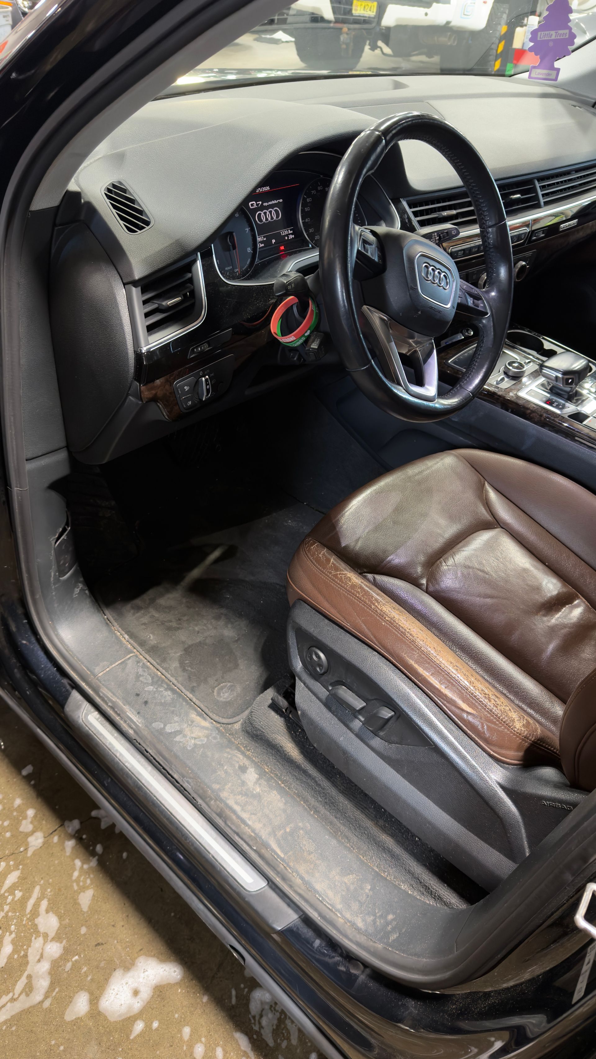 Car interior with brown leather seats, black dashboard, and steering wheel, seen from the open driver’s door