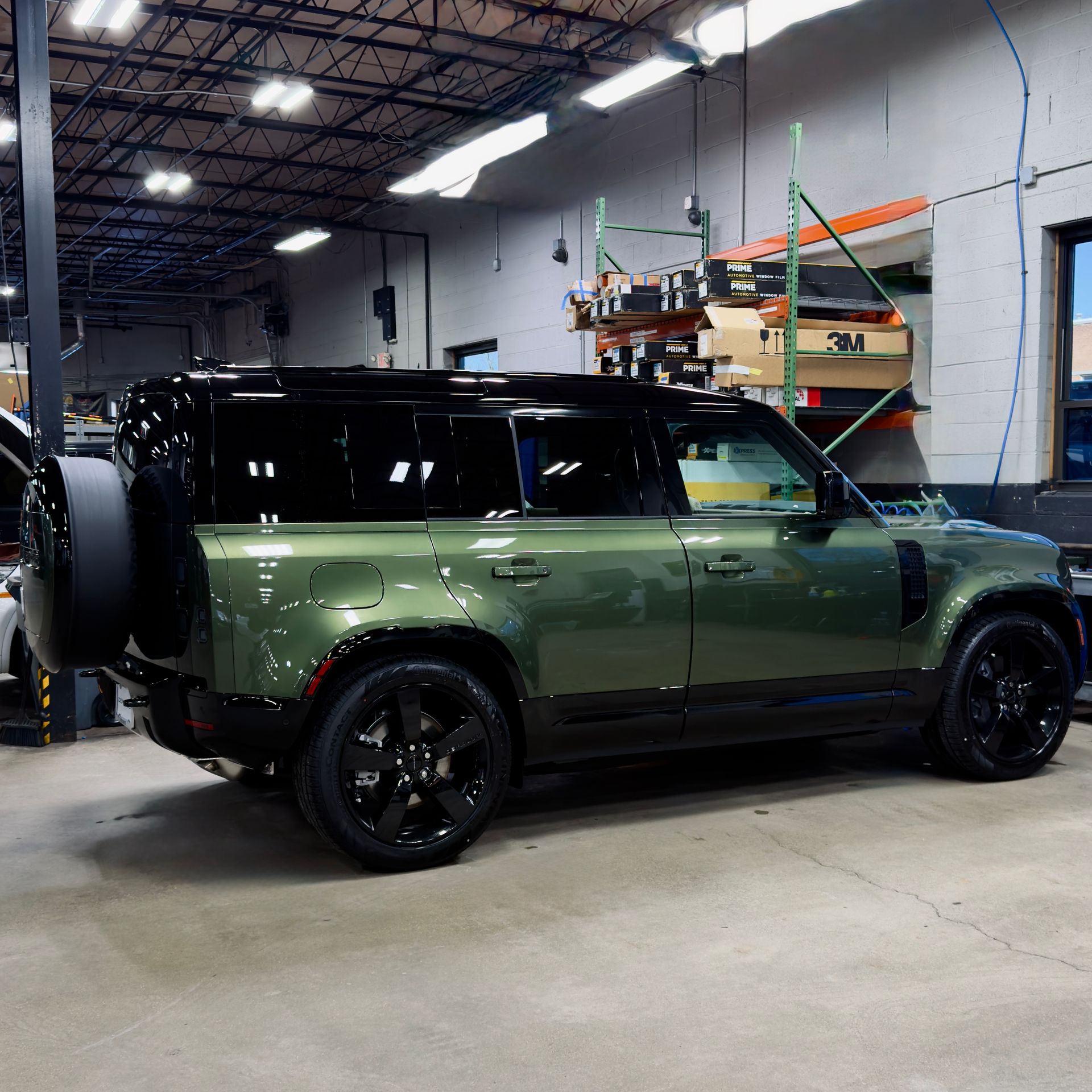 Green SUV with black roof parked inside a garage or workshop