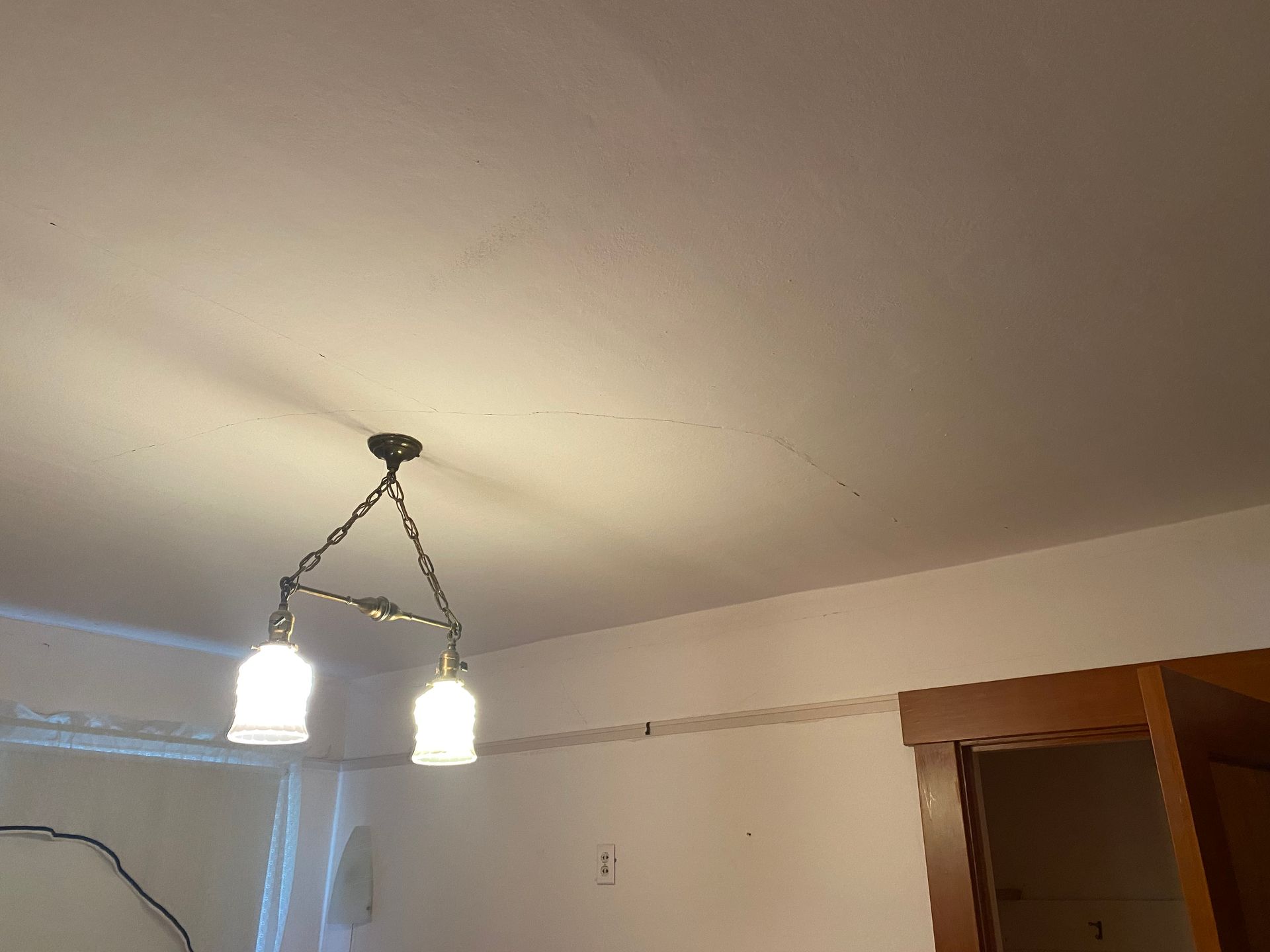 Ceiling light fixture with two frosted glass shades in a room with white walls and wooden trim