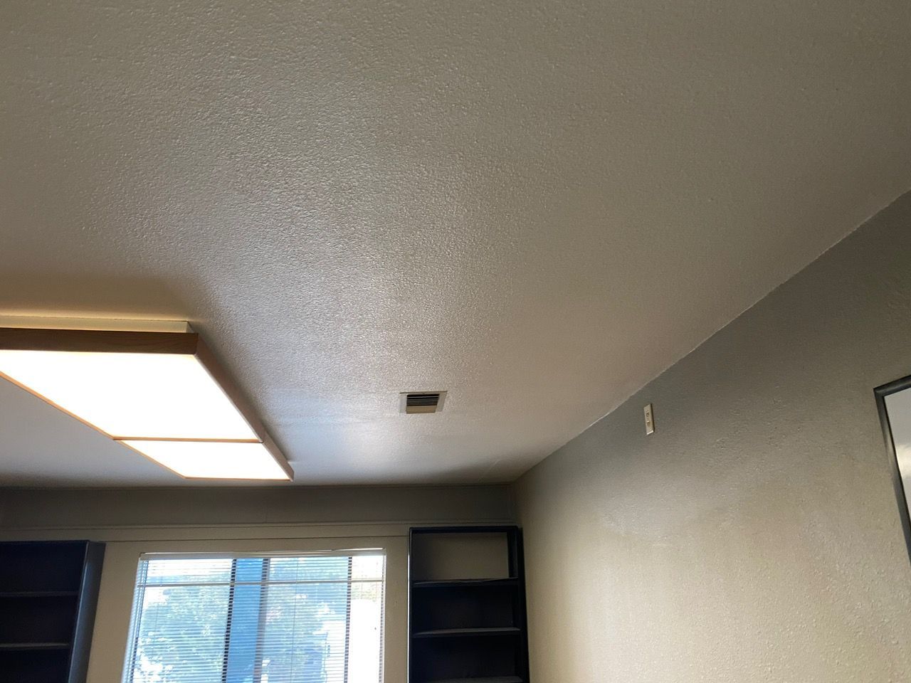 Ceiling and window in a small room with gray walls and a fluorescent light fixture