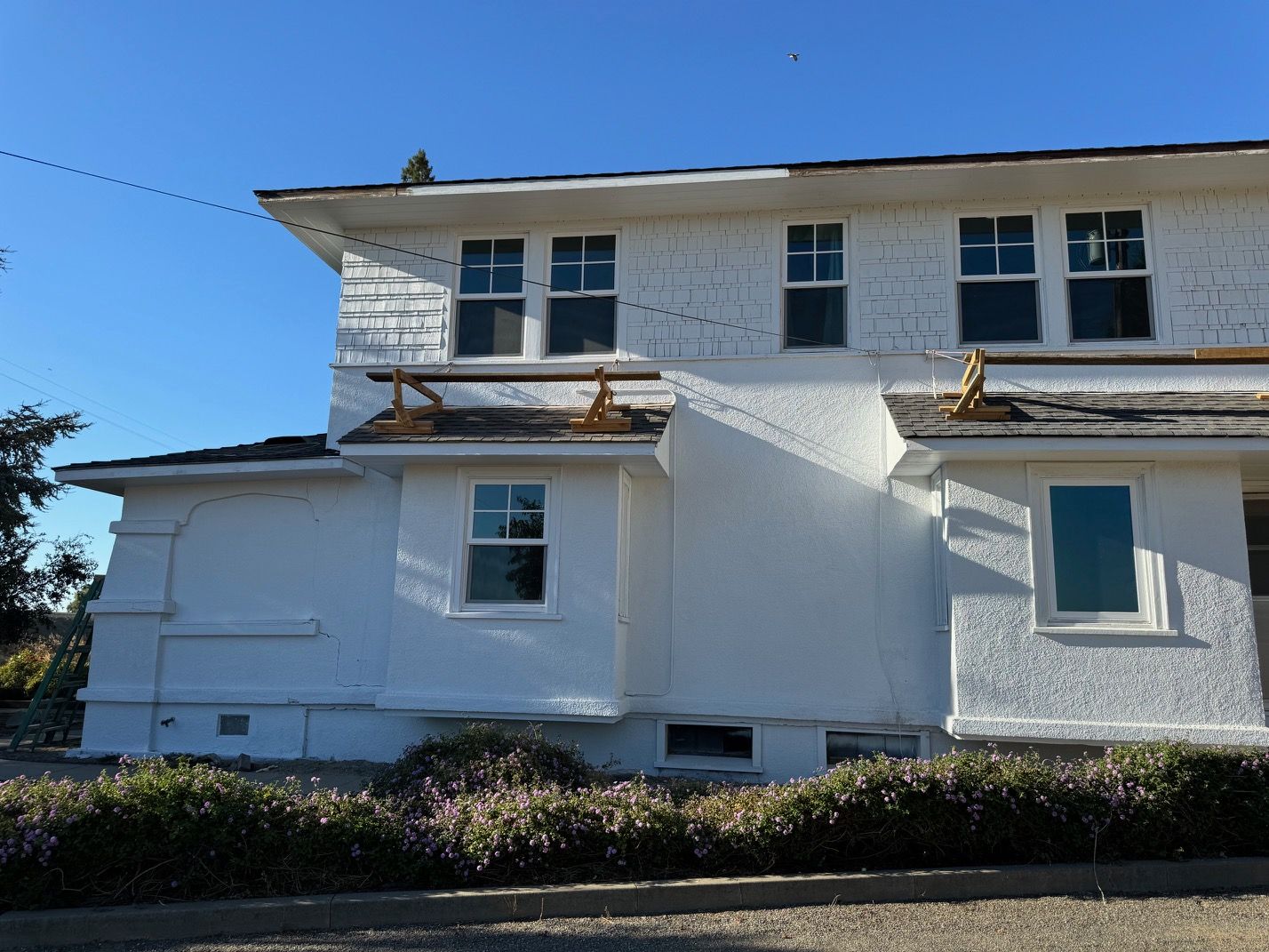 White stucco house with balconies under construction, blue sky overhead