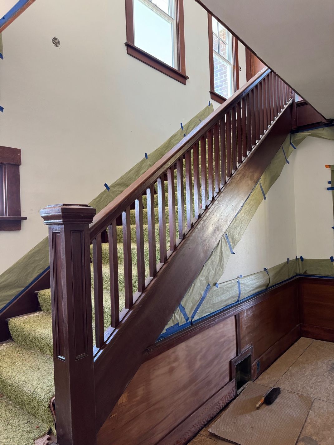 Wooden staircase with dark banister and cream walls in an indoor hallway