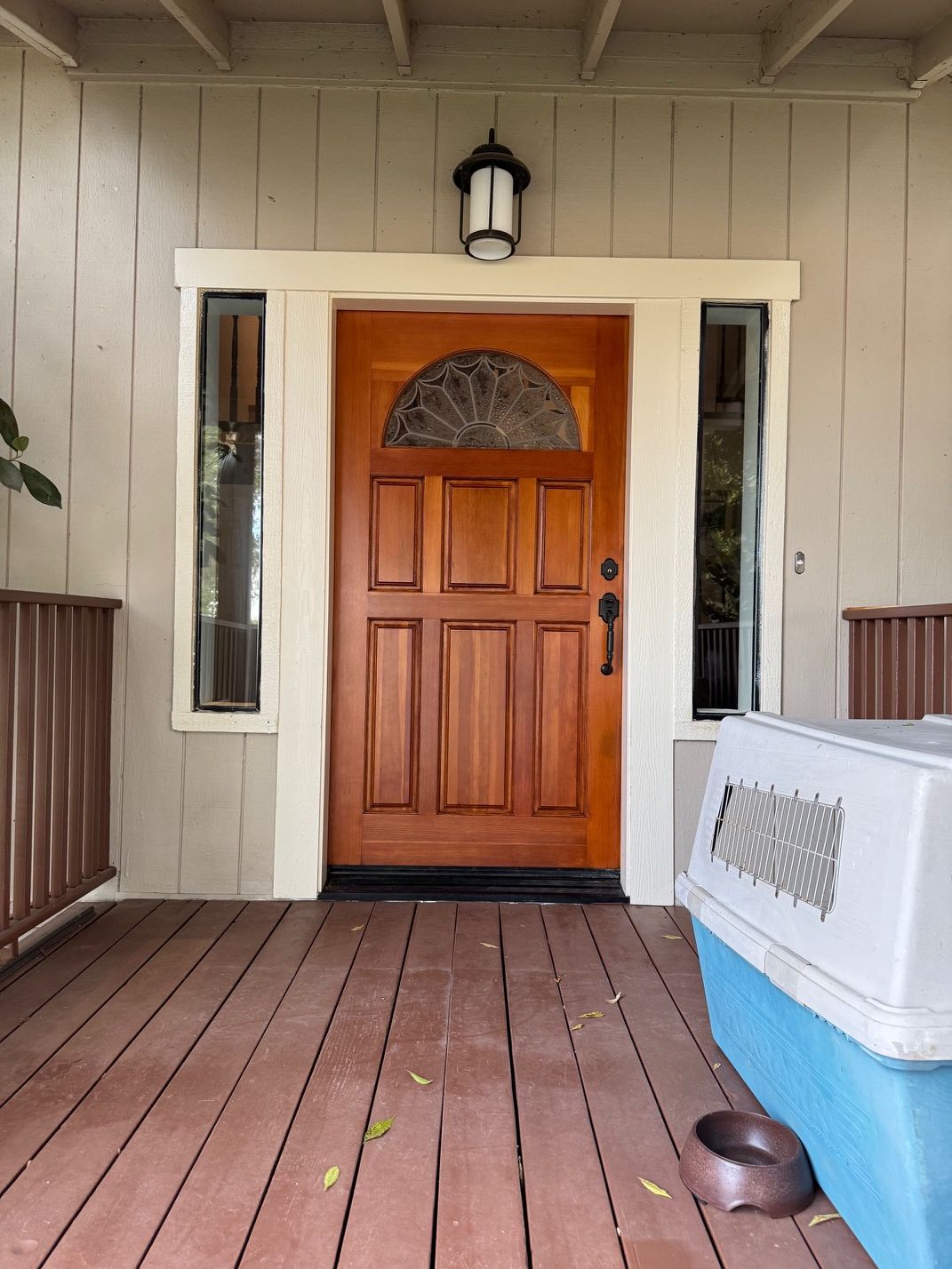 Front porch with a wooden front door, sidelights, and a white cooler on the right.