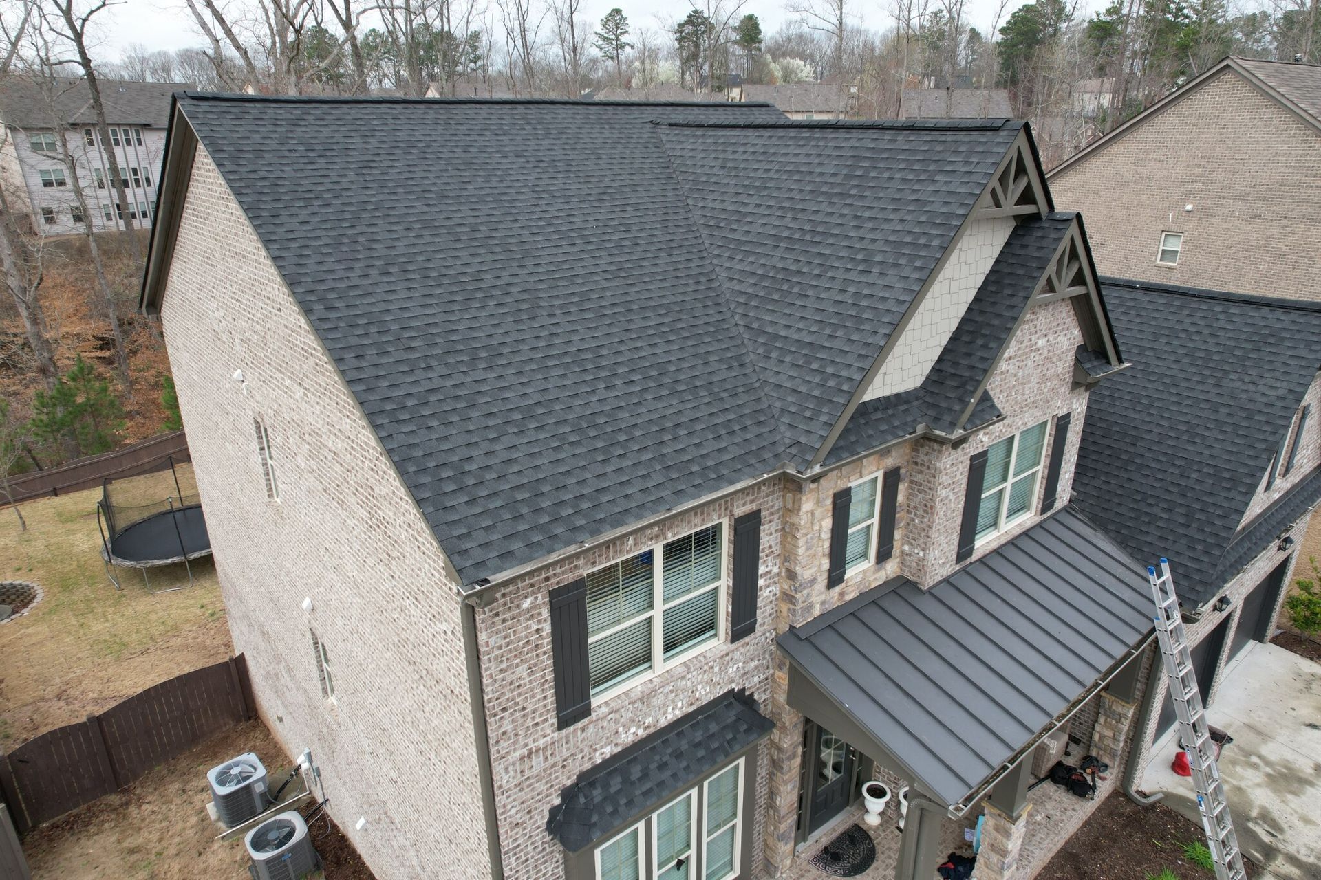 An aerial view of a large brick house with a black roof.
