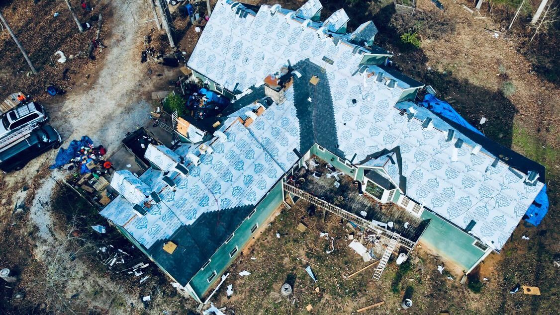 An aerial view of a house under construction with a roof being installed.