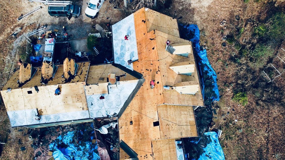 An aerial view of a house under construction with a roof being installed.