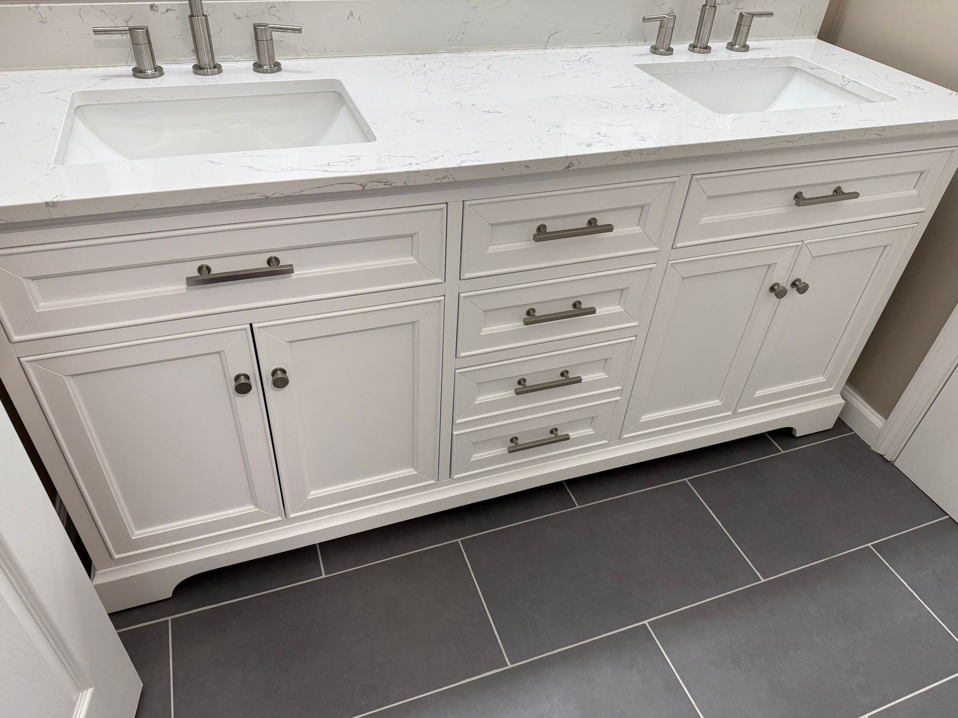 White bathroom vanity with two sinks and gray tiled floor.