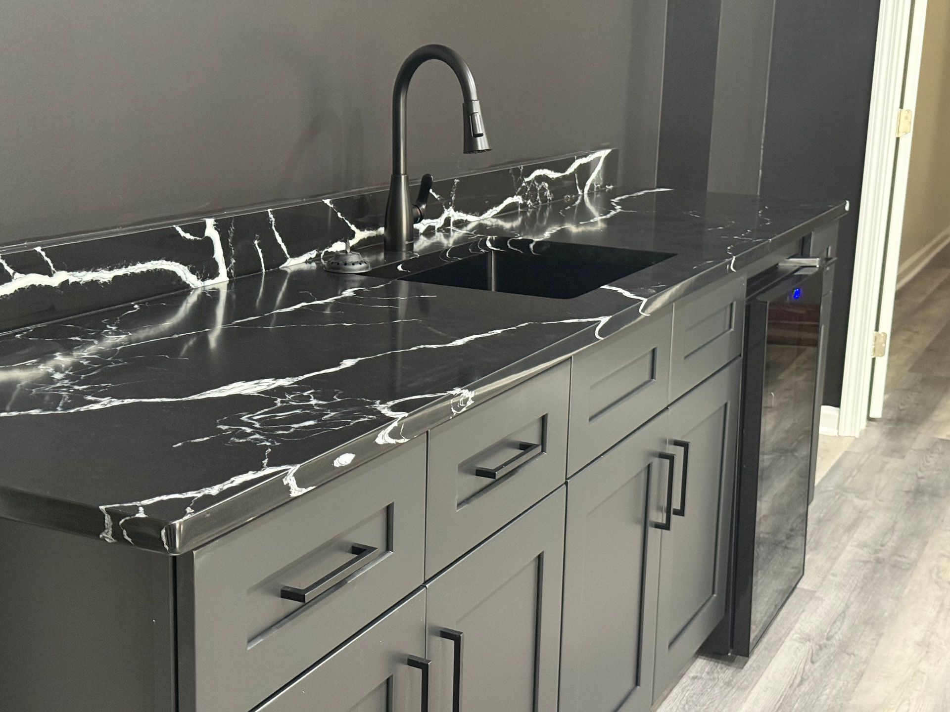 Black and white marble countertop with black cabinets, faucet and sink.