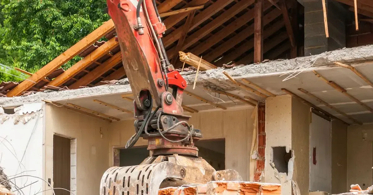 excavator demolishing residential house structure in Central Texas